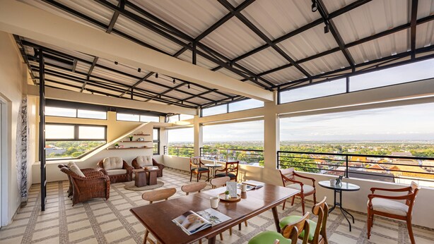 A spacious balcony with a dining area, wicker furniture, and a view of the city. - Cove Nuansa Home (Jimbaran)