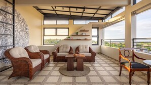 A spacious balcony with wicker furniture, a round table, and a view of the city. - Cove Nuansa Home (Jimbaran)