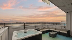 Eine Dachterrasse mit Whirlpool, Sitzgelegenheit und Blick auf die Stadtlandschaft.