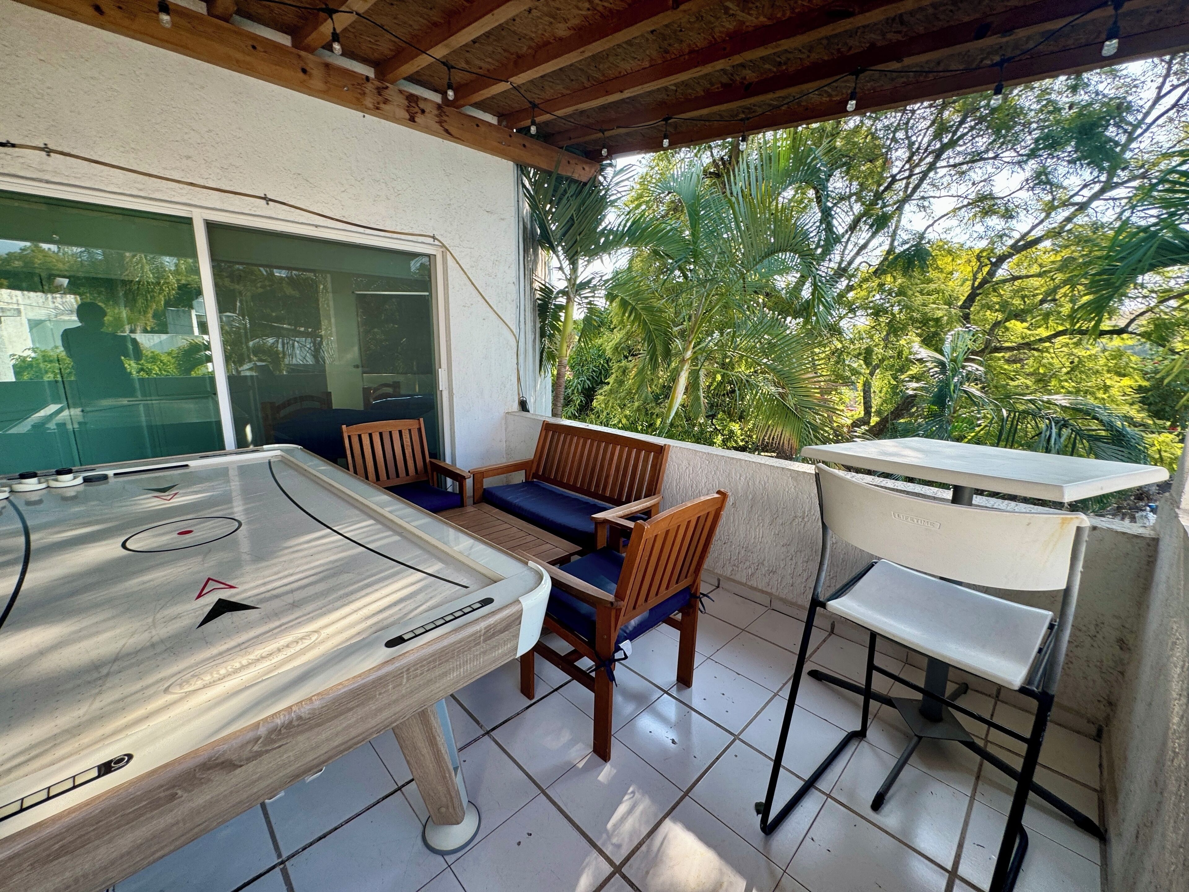 Un patio con una mesa de juego de hojalata, sillas de madera y una mesa blanca.