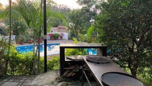 Un espace aménagé au bord de la piscine, comprenant un barbecue, des plantes en pot et une vue sur la piscine.