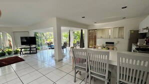 Un grand espace de vie comprenant un coin repas avec table et chaises, un téléviseur à écran plat et une cuisine équipée d’un réfrigérateur et d’une cuisinière.