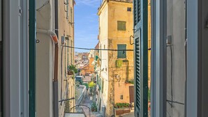 Eine enge Straße mit Gebäuden an beiden Seiten, einer sichtbaren Treppe und blauem Himmel.