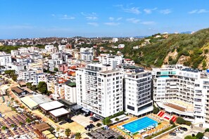 A high-rise hotel with multiple floors, a rooftop pool, and a view of the surrounding cityscape. - Beachfront & Sea View Apartment 101, Durres, Albania (Durres)