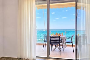 A balcony with a table set for two, overlooking the sea. - Beachfront & Sea View Apartment 101, Durres, Albania (Durres)