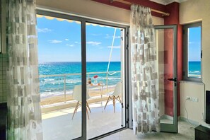 Una habitación con puerta de cristal corredera que da a un balcón con vista al mar.
