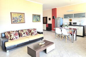 Un salon moderne comprenant un canapé, une table basse et un coin repas avec des chaises et une table.