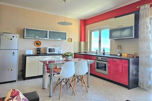 A kitchen with a dining table, chairs, a refrigerator, microwave, stove, and cabinets.
