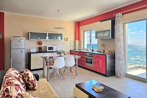 A compact kitchen with a dining area, a sofa, and a view of the sea. - Dream View Apartment Durres 119, Durres, Albania (Durres)
