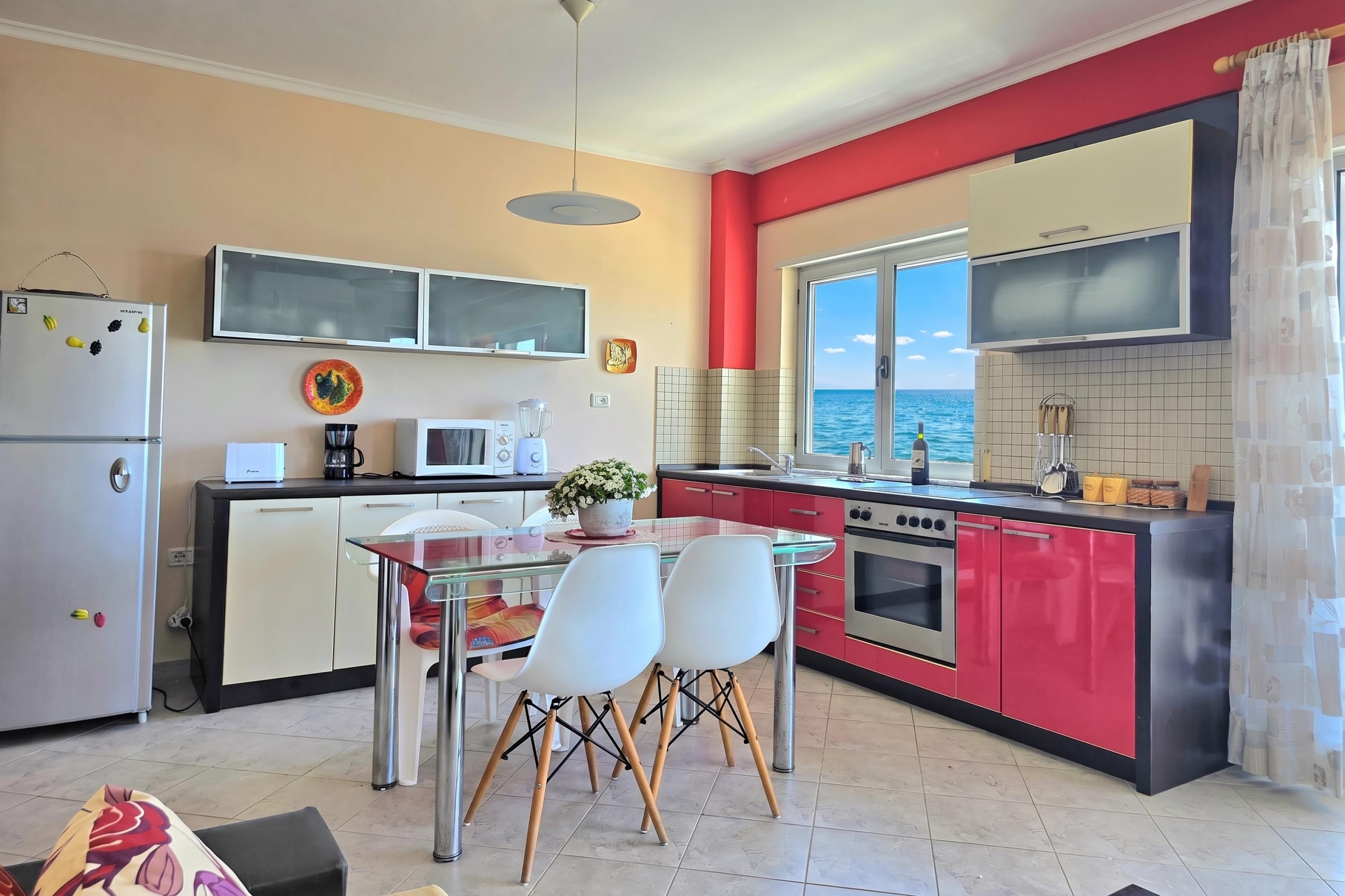 Eine moderne Küche mit Essbereich und Meerblick, gestaltet in Rot und Weiß.