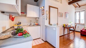 A modern kitchen with white cabinets, a sink, and a dining area with a table and chairs. - Le Fontane With View Lake, Gardone Riviera, Italy (Gardone Riviera)