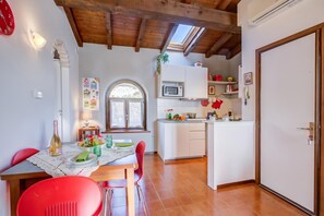 A kitchen with white cabinets, a microwave, and a red chair. - Le Fontane With View Lake, Gardone Riviera, Italy (Gardone Riviera)