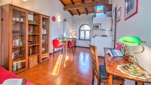 A cozy living room with a wooden ceiling, a dining area with a red chair, and a kitchen with white cabinets. - Le Fontane With View Lake, Gardone Riviera, Italy (Gardone Riviera)