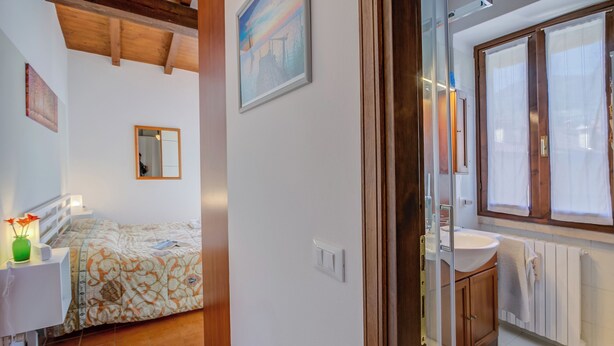 A bedroom with a bed, bedside table, and a mirror. - Le Fontane With View Lake, Gardone Riviera, Italy (Gardone Riviera)