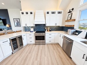 A modern kitchen with white cabinetry, a built-in oven, and a dishwasher. - Ocean front oasis full remodel hot tub heated pool Wild horses 8 bed 8 bath (Corolla)
