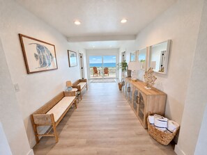 A hallway with a bench, a console table with a lamp, and a view of the ocean. - Ocean front oasis full remodel hot tub heated pool Wild horses 8 bed 8 bath (Corolla)