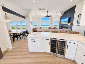 A modern kitchen with a large island, white cabinetry, and a view of the beach. - Ocean front oasis full remodel hot tub heated pool Wild horses 8 bed 8 bath (Corolla)