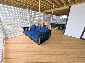 A wooden deck with a swing seat and a small table. - Ocean front oasis full remodel hot tub heated pool Wild horses 8 bed 8 bath (Corolla)
