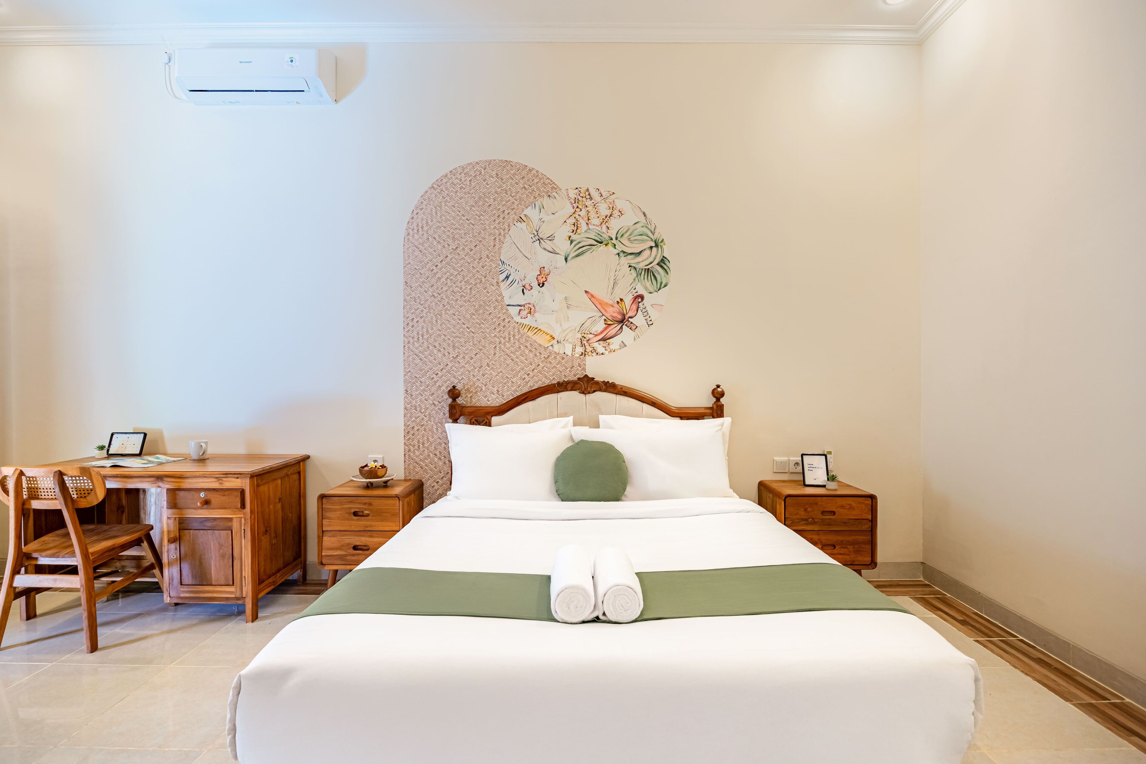 A neatly arranged hotel room with a wooden bed, a desk, and a chair.