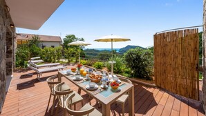 Un área de comedor al aire libre con una mesa lista para el desayuno, con vista a un paisaje pintoresco.