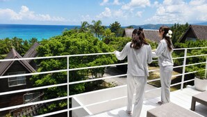 A balcony with a view of the ocean and tropical vegetation. - A Premium Okinawa Villa Stay with Sauna & Jacuzzi (nakama, Onna Village)