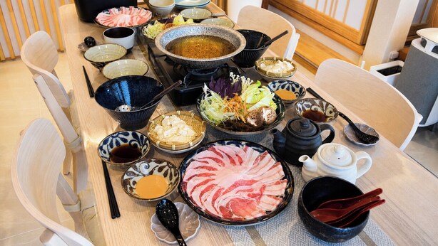 A traditional Japanese hot pot meal setup with various ingredients and condiments. - A Premium Okinawa Villa Stay with Sauna & Jacuzzi (nakama, Onna Village)