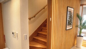 A wooden staircase with a handrail, a potted plant, and a framed picture on the wall. - A Premium Okinawa Villa Stay with Sauna & Jacuzzi (nakama, Onna Village)