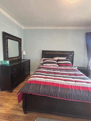 A bedroom with a bed, a dresser, a mirror, and a nightstand.