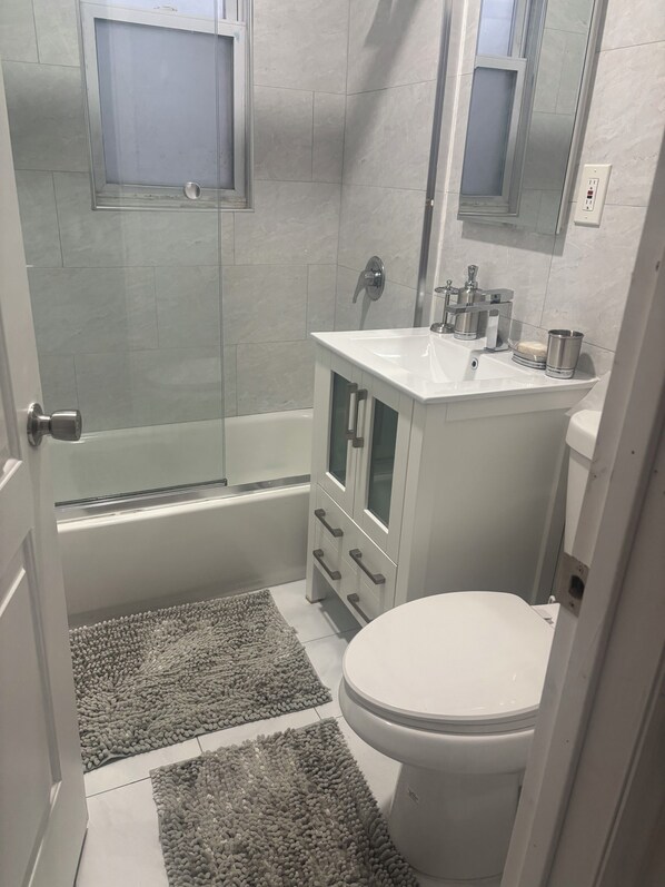 A bathroom with a bathtub, toilet, sink, and a mirror.