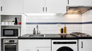 Uma cozinha compacta com micro-ondas, forno, pia e lava-louças.