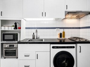 Eine kompakte Küche mit Mikrowelle, Backofen, Spüle und Geschirrspüler.