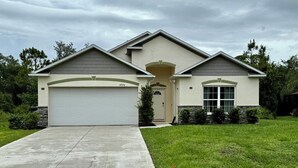A single-story house with a garage, a front entrance, and a well-maintained lawn. - Peaceful 4-BR resting place (North Port)