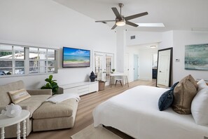 A spacious bedroom with a large bed, a ceiling fan, and a view of the beach through large windows. - Olde Naples Beach House. Newly renovated, walk to beach and Four Seasons Resort (Naples)