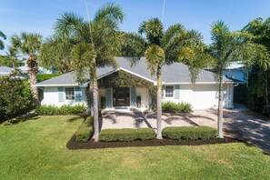 A single-story house with a sloped roof, surrounded by palm trees and well-maintained lawns. - Olde Naples Beach House. Newly renovated, walk to beach and Four Seasons Resort (Naples)
