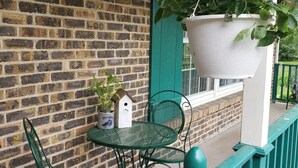 A brick wall, a green metal table with two chairs, a hanging planter with a plant, and a white birdhouse on the table. - Newly Remodeled 2BR 2BA Home  Close to Barrington (Barrington)