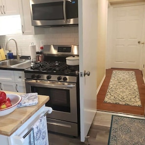 A kitchen with a stove, oven, microwave, and a sink. There is a door leading to another room. - Newly Remodeled 2BR 2BA Home  Close to Barrington (Barrington)