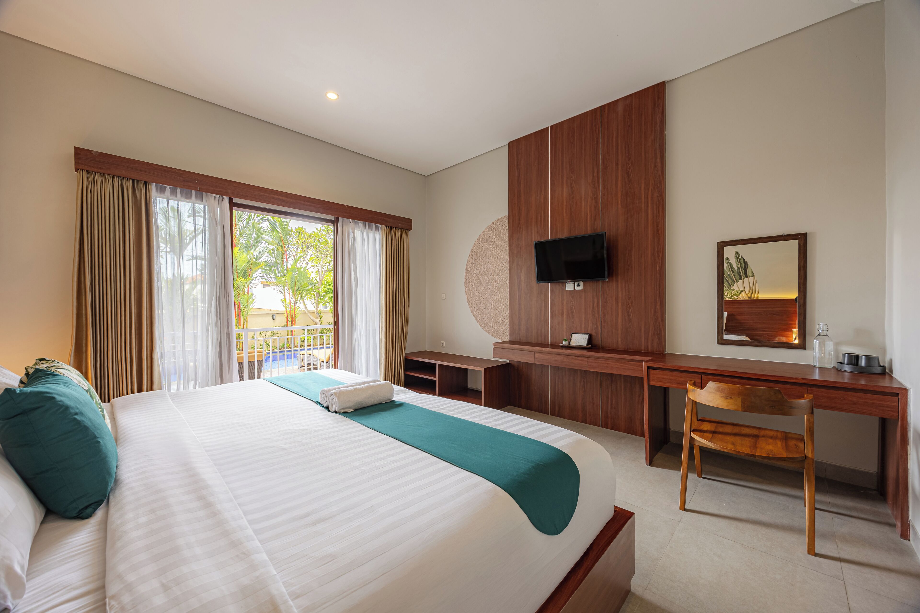 A hotel room with a large bed, a desk, a chair, a TV, and a window with curtains.