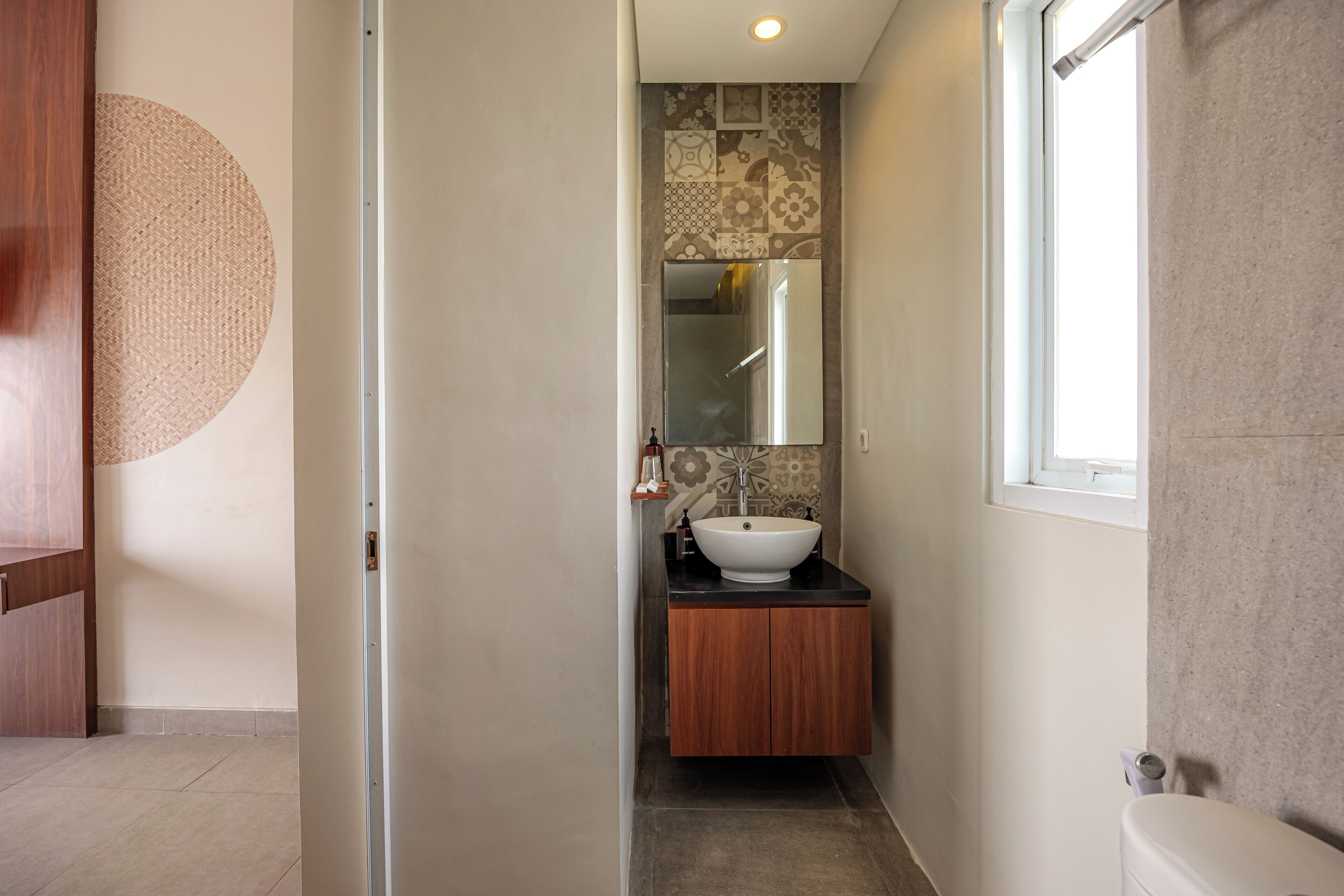 Un baño estrecho con un mueble de madera, un lavamanos blanco y un espejo.