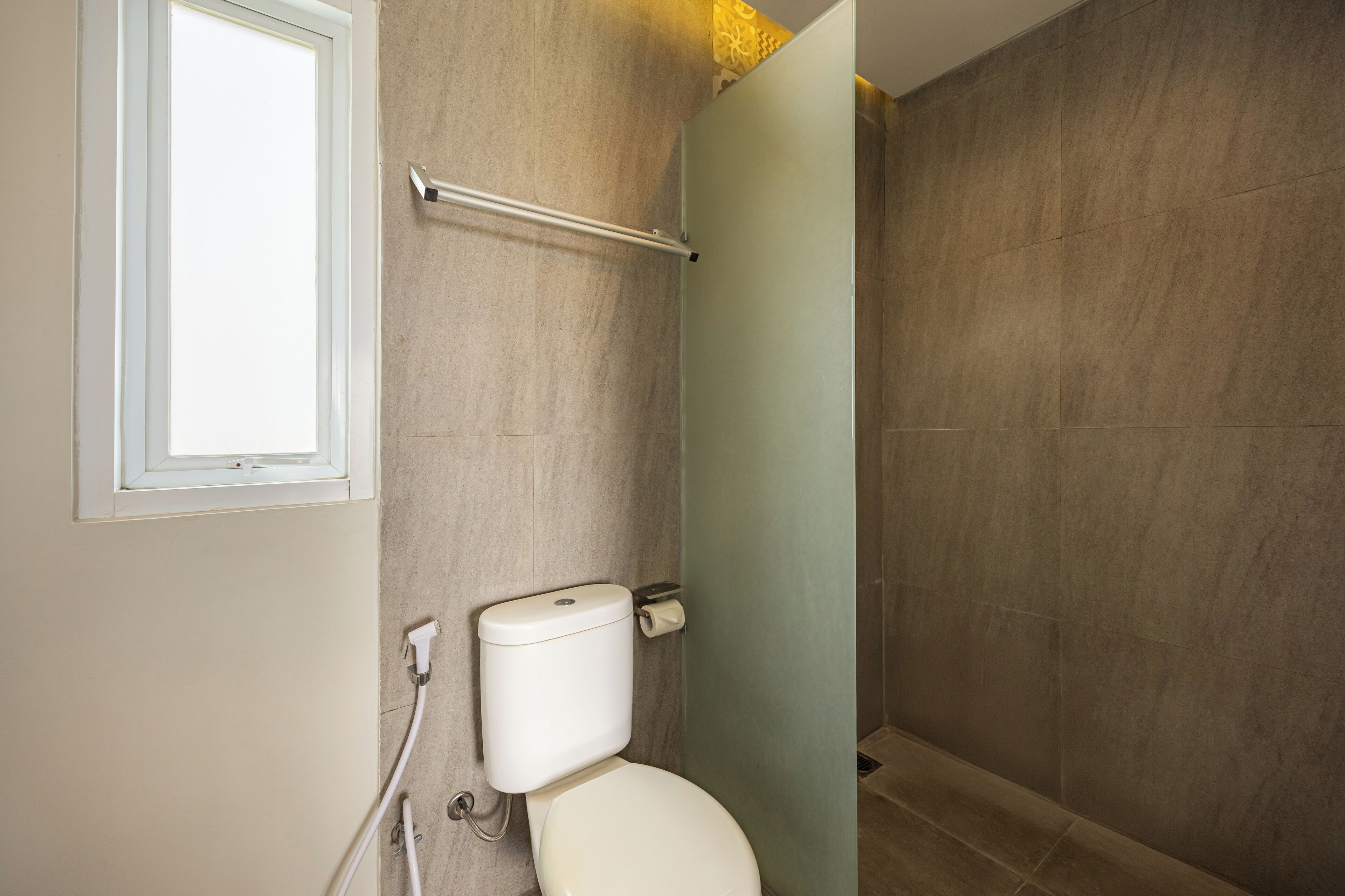 A bathroom with a toilet, a towel rack, and a shower area.