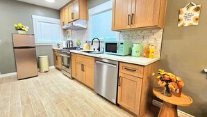 A modern kitchen with wooden cabinets, stainless steel appliances, and a small round table with flowers. - Charming & Cozy Home Near Caltech PCC & Pasadena Convention Center King-size bed (Pasadena)