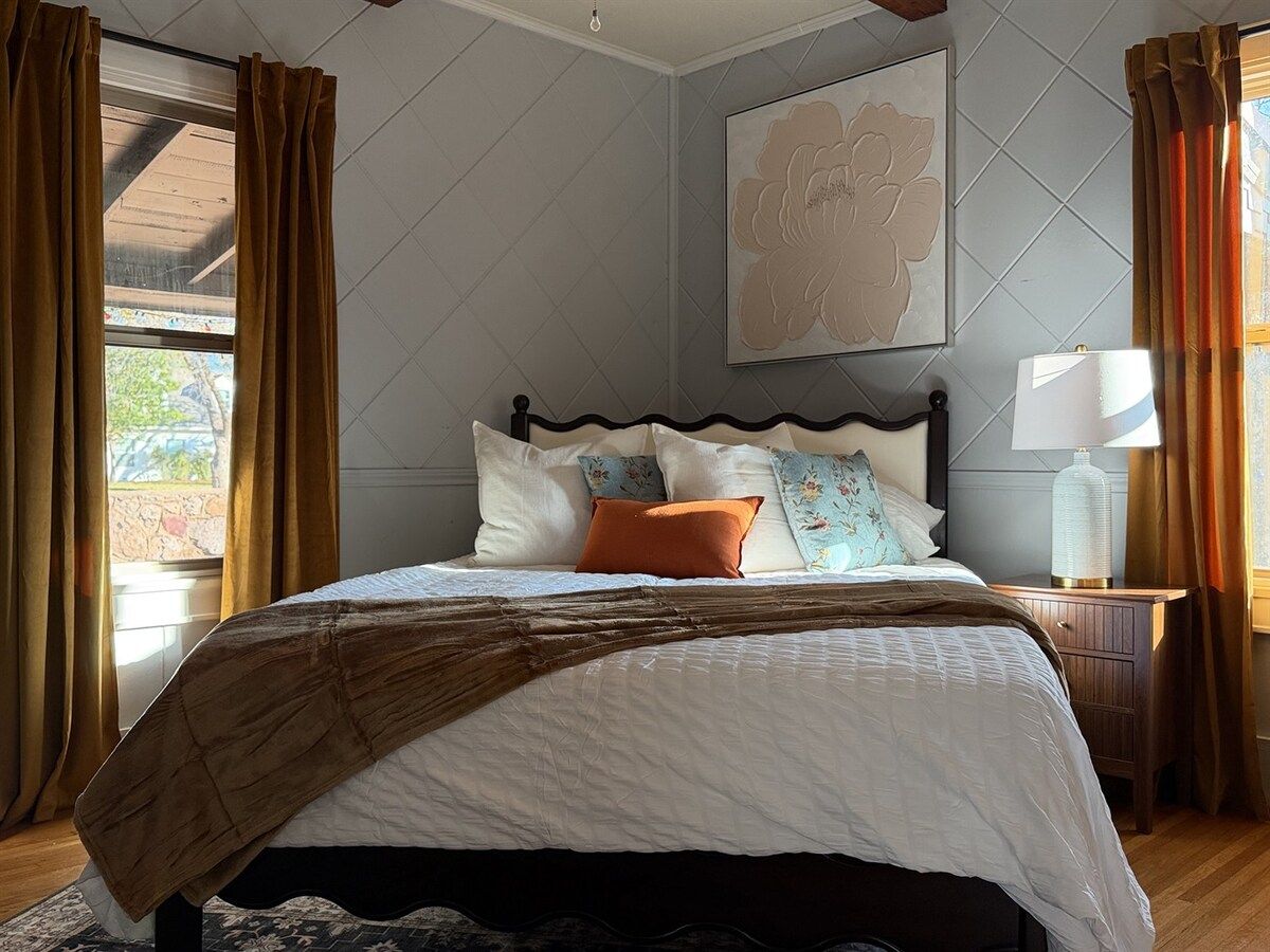 A bedroom with a bed, a nightstand, a lamp, and a window with curtains.