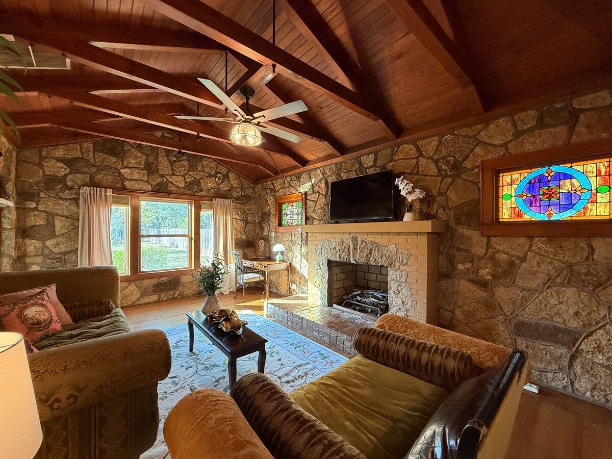 A cozy living room with a stone fireplace, wooden ceiling beams, and a comfortable seating area.