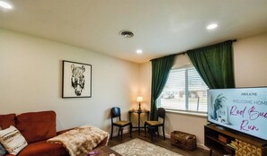 A living room with a sofa, a TV, a lamp, and a framed picture on the wall. - Red Bud Run - Stylish Abilene Retreat (Abilene)