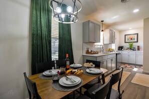 Una cocina moderna con armarios grises, una mesa de comedor de madera dispuesta con platos, vasos y una botella de vino.