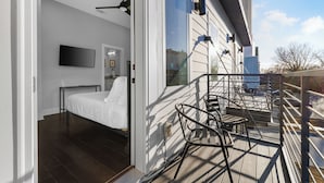 Una camera da letto con un letto, una TV e un balcone con sedie.