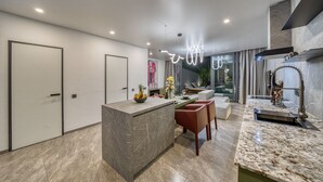 Una cocina moderna con una isla de mármol, sillas rojas y una zona de comedor con sofá y mesa.