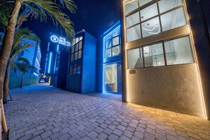 A modern building with a blue facade, a visible entrance, and a number '103' on the wall. - XO Canggu - Adults Only (Canggu)