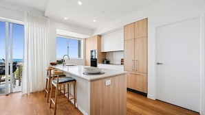A modern kitchen with a central island, wooden cabinets, and a view of the ocean. - Ocean Views Kings Beach (Kings Beach)