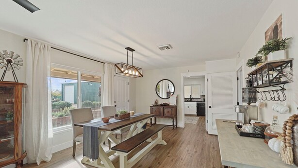 A spacious living room with a wooden dining table, a bench, and a kitchen in the background. - Wellness at the Ranch Retreat! 2 Bedroom 2 Bath Oasis with outdoor living space (Acampo)