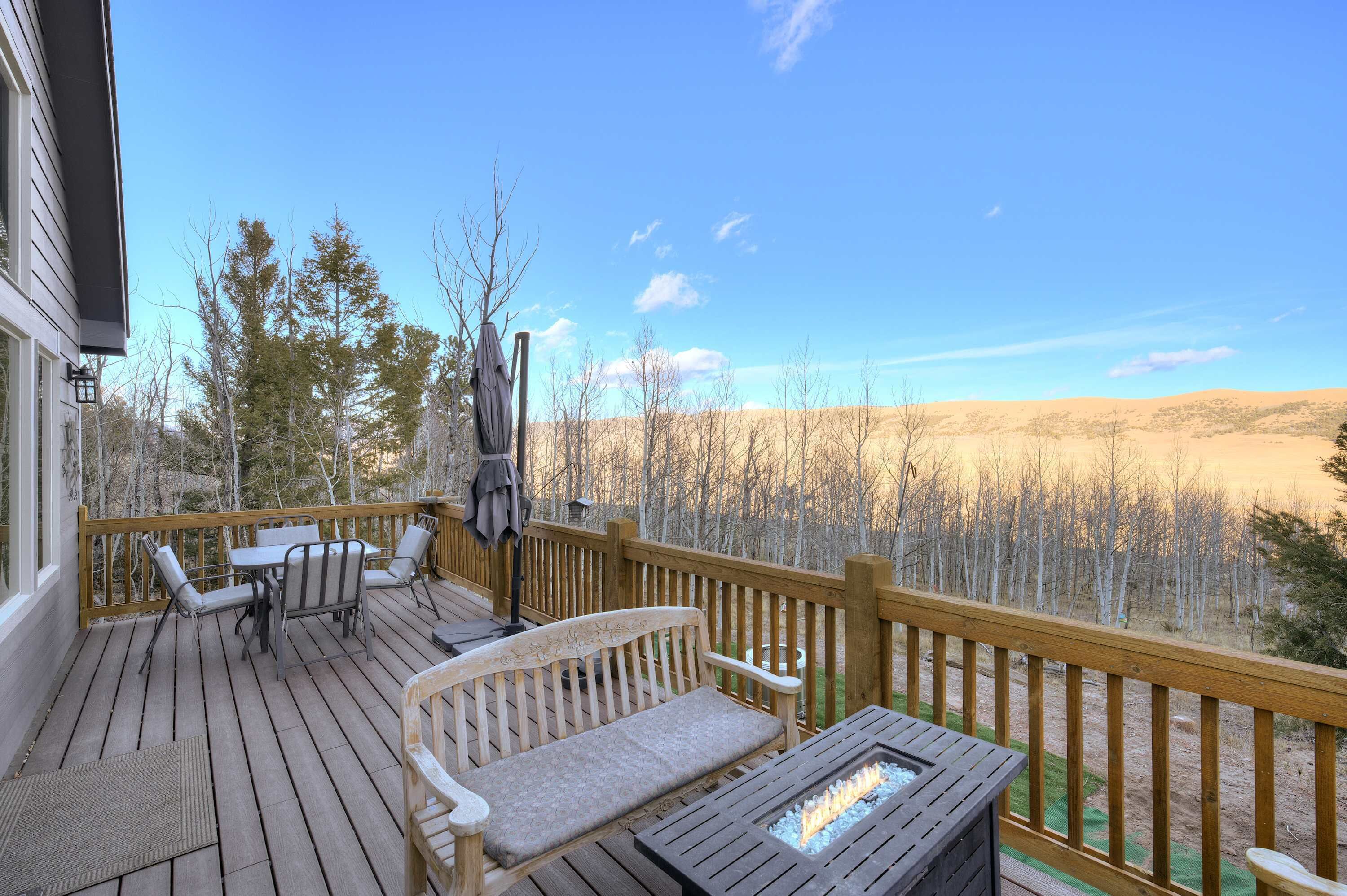 A wooden deck with outdoor furniture, including a table and chairs, and a bench.